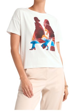 T-shirt à manches courtes blanche avec un imprimé abstrait coloré de deux figures. Tissu doux avec une coupe décontractée, associé à un pantalon de couleur claire.