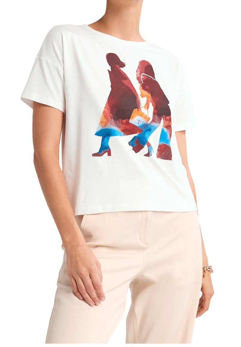 T-shirt à manches courtes blanche avec un imprimé abstrait coloré de deux figures. Tissu doux avec une coupe décontractée, associé à un pantalon de couleur claire.