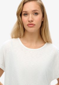 Witte t-shirt met korte mouwen van een zachte, gestructureerde stof en een ronde halslijn, met opgerolde mouwen en een ontspannen pasvorm.