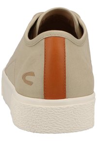 Beige canvas shoe with a smooth brown leather accent at the back. Features a textured rubber sole and a minimalistic design.