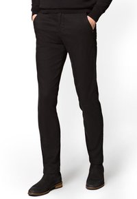 Czarne, dopasowane spodnie wykonane z bawełny. Posiadają dwie boczne kieszenie i gładką teksturę, w zestawie z czarnymi botkami za kostkę.