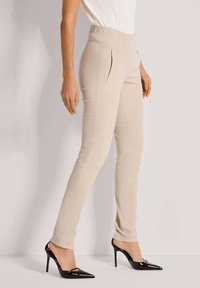 Beige slim-fit broeken met voorzakken, gemaakt van een soepele stof. Gecombineerd met zwarte hoge hakken met een puntige neus en slingback ontwerp.