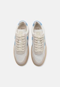 Lys grå lær sneakers med blå detaljer, en perforert tåboks og beige snøringer. Har en gummisåle i naturlig gummi og en logo på tungen.