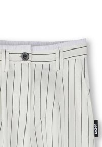 Pantalones blancos con rayas verticales negras, que cuentan con un cierre de botón, una cinturilla elástica y una etiqueta DKNY en el lateral. Textura suave.