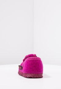 Fuchsia wollen pantoffel met een gestructureerd oppervlak, ronde achterkant en een contrasterende donkere zool. Bevat een kleine logo-label aan de zijkant.