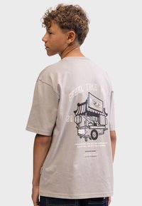 Gray cotton t-shirt with a relaxed fit, featuring a bold graphic of a food cart on the back, and textual elements in black and white.