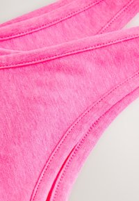 Roze katoenen slipjes met een gladde textuur, voorzien van smalle bandjes en platte naden voor comfort. Minimalistisch ontwerp en levendige kleur.