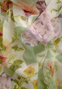 Genomskinlig tyg med ett blommönster i rosa, gult och grönt. Lätt, texturerad nät med mjuk drapering.