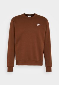 Brun långärmad Nike-tröja med rund halsringning och vitt Nike-logotyp på vänster bröst, uppställd mot en enkel bakgrund.