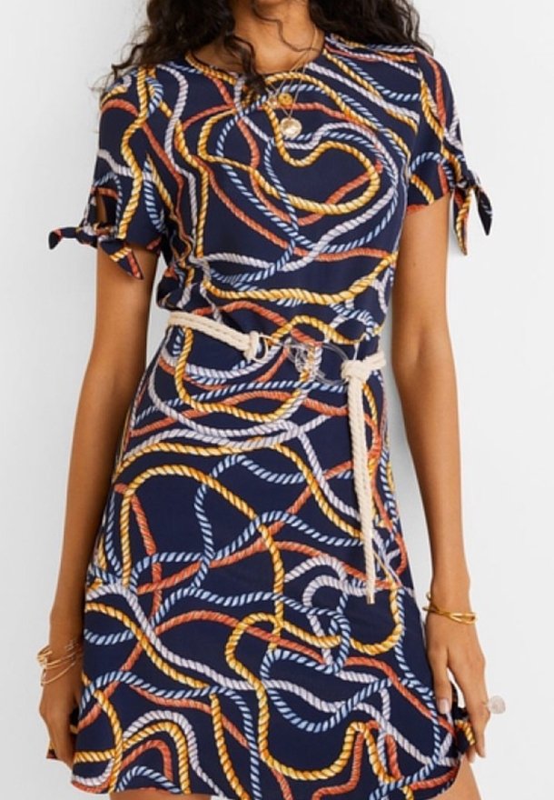 Námořnické šaty s tkanej vzorem v bílé, oranžové a žluté barvě. Krátké rukávy se saténovými stuhami a látkovým páskem v oblasti pasu.