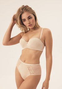 Beżowy stanik z gładkimi miseczkami i regulowanymi ramiączkami, w połączeniu z majtkami o wysokim stanie z koronkowymi akcentami i siateczkowymi panelami.