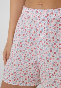 Bavlněné šortky s květinovým vzorem, s elastickým pasem, růžovým pozadím, drobnými červenými a modrými květy a knoflíkovými detaily.