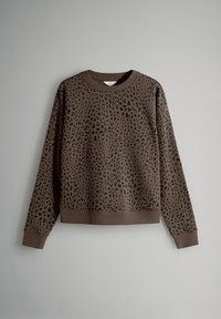 Brun sweatshirt med svart leopardmönster, långa ärmar och ribbade muddar och fåll, visad mot en enkel ljusgrå bakgrund.