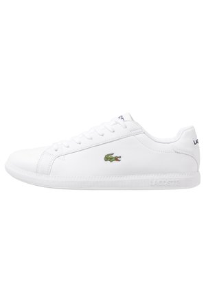 Hvid lavskoet Lacoste sneakers med grønt krokodillelogo på siden, hvide snørebånd og præget Lacoste-mærke på sålen.