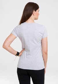 Gray short-sleeve t-shirt made of soft fabric, featuring a round neckline and a straight cut. Worn with black pants, showing a simple design.