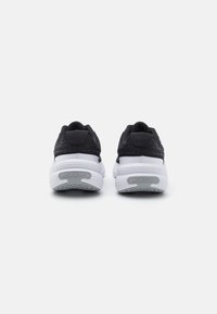 Crne atletske tenisice s pjenastim bijelim srednjim dijelom, s teksturiranim gornjim dijelom i istaknutim Nike logotipom na peti.