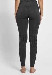 Leggings grigi con vita alta, pannelli testurizzati alle ginocchia e un design ornamentale sul retro, caratterizzati da una finitura liscia.