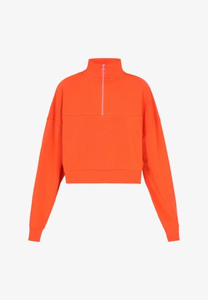 Skraćeni dukserica u svijetlo narančastoj boji, izrađena od mekanog materijala. Ima visoki ovratnik s ružičastim patentnim zatvaračem i široke, duge rukave.