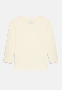 Μακρυμάνικο t-shirt σε ανοιχτό κίτρινο χρώμα από βαμβάκι, με στρογγυλή λαιμόκοψη και ίσια ραφή στο τελείωμα. Χωρίς ορατά σχέδια ή γραφικά στην πλάτη.