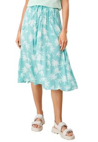 Jupe mi-longue légère turquoise à motif de palmiers blancs, taille élastique et coupe fluide, portée avec des sandales blanches.