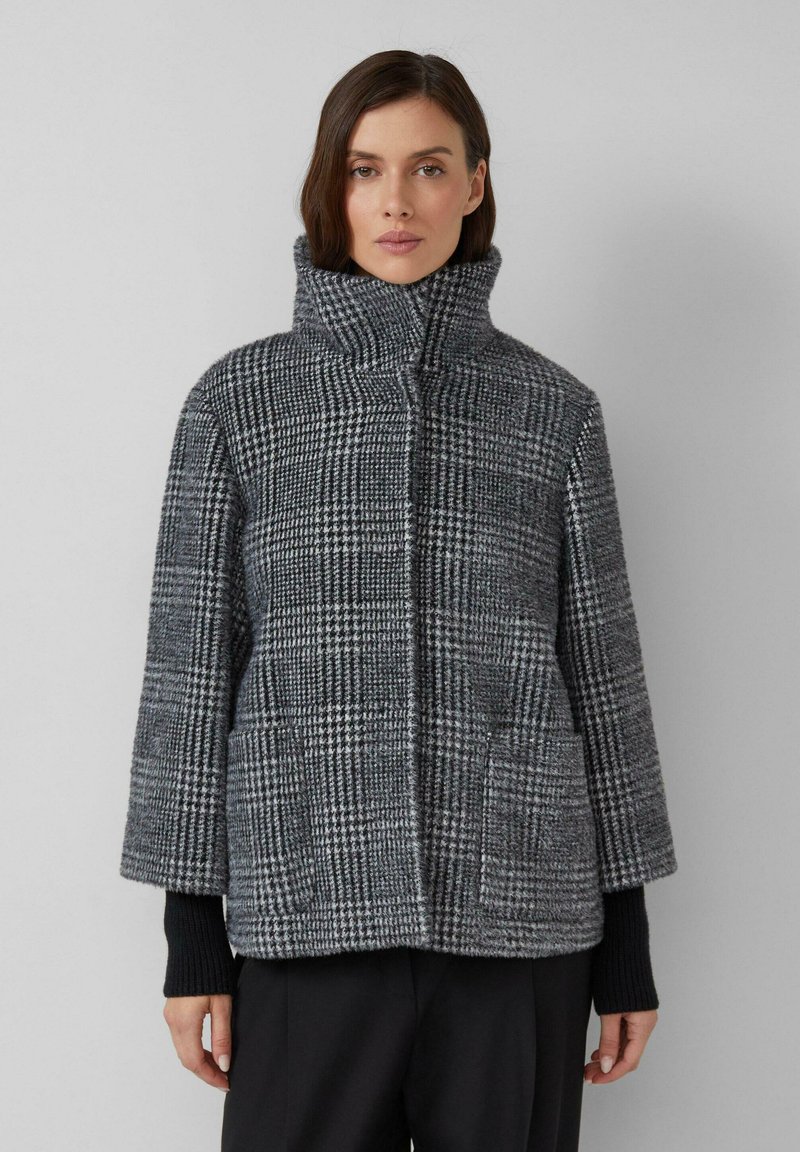 Szary i czarny płaszcz w kratę z wysokim kołnierzem, przestronnymi rękawami, przednimi kieszeniami oraz teksturowanym materiałem.