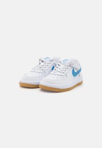 Hvite Nike-sneakers med blå detaljer. Glatt lær overdel, perforert tåboks og gummisåle. Snøring med polstret krage.