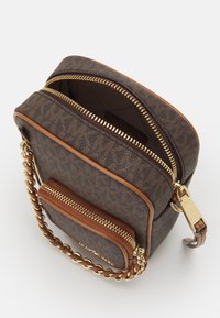Borsa a tracolla di design marrone con zip dorata e tracolla a catena, tasca frontale e scomparto principale parzialmente aperto su sfondo bianco.