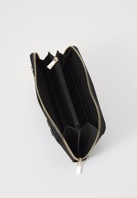 Black wallet featuring a zip closure, multiple card slots, and an interior zipper pocket. Soft textured material with gold-tone hardware accents.