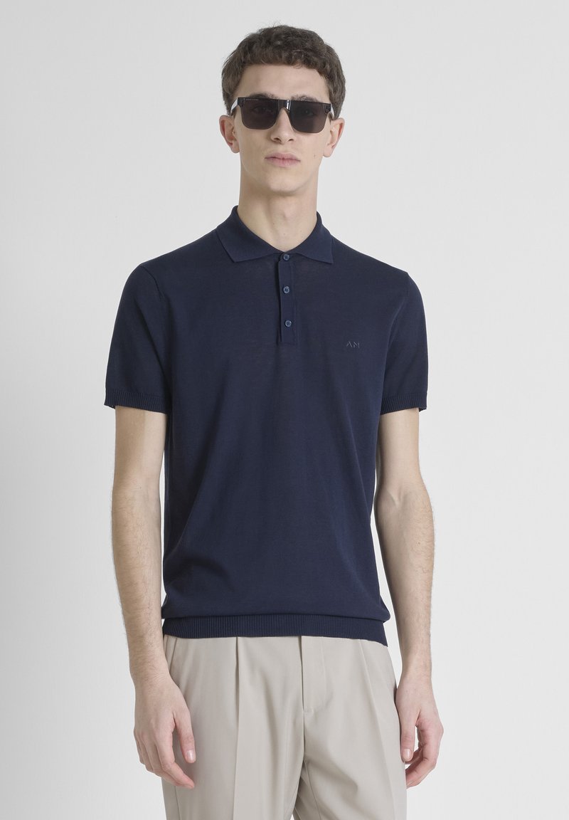 Polo shirt blu navy con una texture morbida, maniche corte e colletto a tre bottoni. Presenta un logo discreto sul petto e polsini a coste.