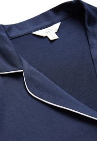 Marineblauer Kleidungs-Kragen mit weißem Paspeldetail und einem Etikett mit der Aufschrift THE SET, Größe Medium, hergestellt in Marokko.