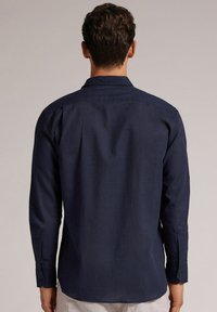 Navy Baumwollhemd mit langen Ärmeln, klassischem Kragen, knöpfbaren Manschetten und geradem Rückendesign. Glatte Textur und einfache Verarbeitung.