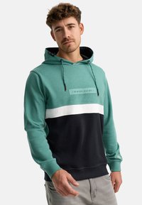 Felpa con cappuccio in teal, blu navy e bianco; presenta una patch testurizzata sul petto con le coordinate; misto cotone; tasca a marsupio; polsini e orlo a costine.