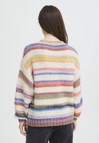 Pull en maille rayé couleur crème, avec des lignes horizontales rose, bleu, vert et violet. Coupe ample avec un col rond.