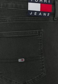 Μαύρα τζιν παντελόνια με πίσω τσέπη που διαθέτει κεντημένο λογότυπο σε ναυτικό, κόκκινο και λευκό χρώμα. Το ύφασμα έχει λεία υφή.