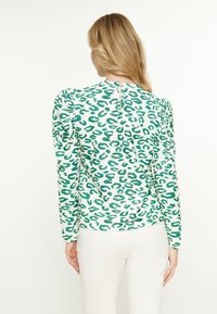 Maglia a maniche lunghe verde e bianca con un tessuto texturizzato a coste che presenta una fantasia leopardata e un piccolo dettaglio a forma di chiave sul retro.