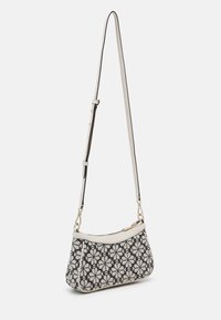 Sac en bandoulière présentant un tissu noir avec un motif floral blanc, des accents en cuir crème, une fermeture éclair et une sangle ajustable.