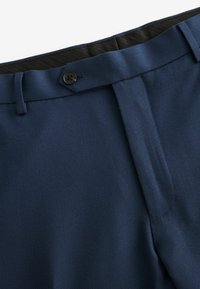Pantalones azul marino con una tela texturizada. Presenta una cinturilla negra y un botón negro en la parte superior. Confeccionados con pliegues en la parte frontal.