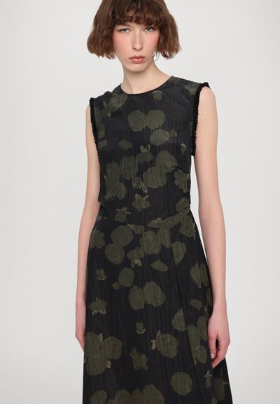 Zwarte jurk met groene bloemenprints, mouwloos ontwerp, gestructureerde stof en franjes langs de halslijn.