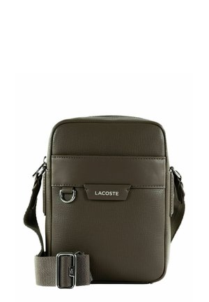 Petit sac bandoulière carré Lacoste marron foncé avec surface texturée, bandoulière en tissu réglable et plaque logo sur le devant.