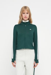 Tamnozeleni zip-up jakna s visokim ovratnikom, kontrastnim bijelim bočnim trakama i uskim krojem. Izrađena od glatkog, rastezljivog materijala.