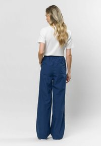 Biały pr�ążkowany top z krótkim rękawem w połączeniu z luźnymi granatowymi spodniami z elastycznym paskiem w talii i kieszonką z tyłu.