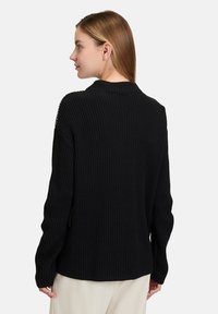 Schwarzer gerippter Pullover mit hochgeschlossenem Kragen und langen �Ärmeln. Verfügt über ein strukturiertes Strickmuster, das für eine lässige Passform mit seitlichen Schlitzen ausgelegt ist.
