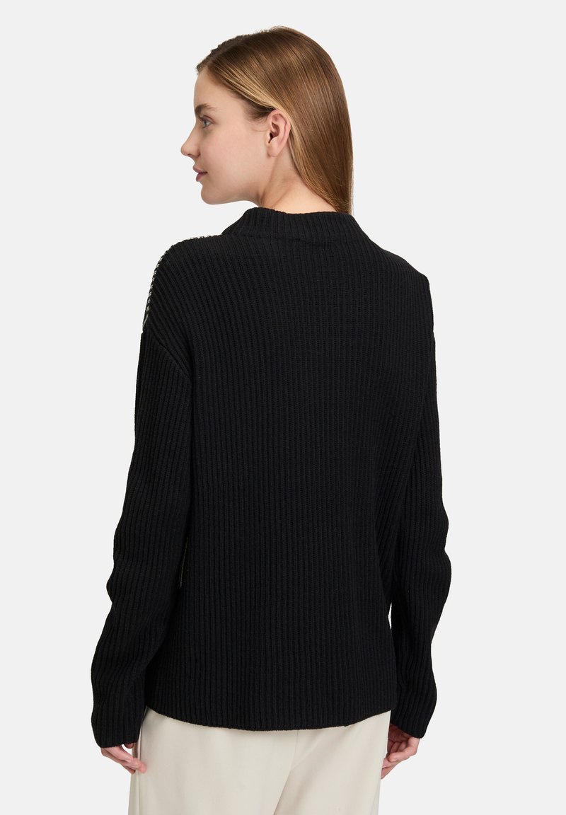 Schwarzer gerippter Pullover mit hochgeschlossenem Kragen und langen Ärmeln. Verfügt über ein strukturiertes Strickmuster, das für eine lässige Passform mit seitlichen Schlitzen ausgelegt ist.