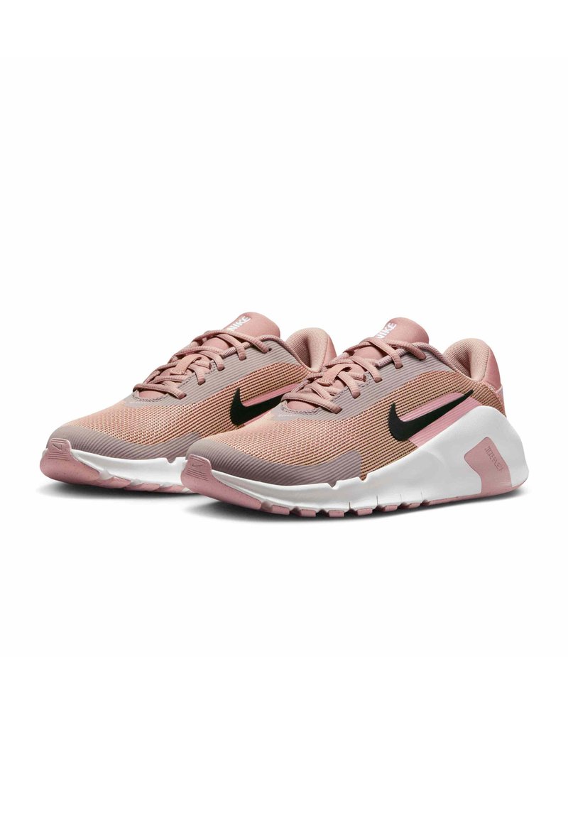 Nike athletic shoes in light pink and gray mesh, featuring black swoosh logo, textured upper, and white rubber sole with pink accents.