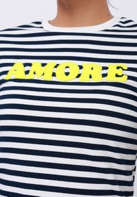 Navy and white striped t-shirt with a round neckline featuring a fluffy yellow "AMORE" embroidery at the center. Soft cotton fabric.