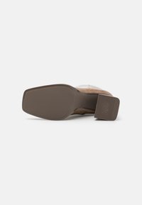 Bruine leren schoen met een gestructureerde rubberen zool, voorzien van een chunky hak en een antislipontwerp. Gestoorde accenten sieren het bovenwerk.
