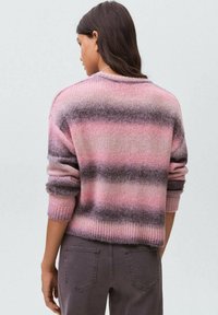 Suéter a rayas rosa y gris con un corte holgado y puños acanalados. Textura suave, escote redondo y mangas enrolladas de manera casual.