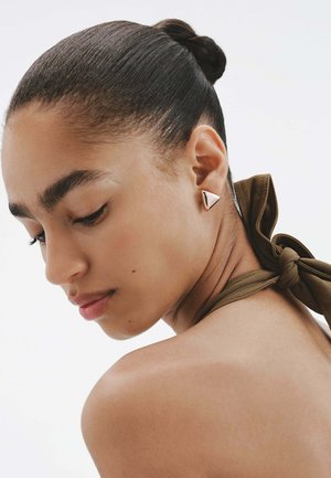 Pendientes de clip triangulares en oro rosa pulido, llevados en la oreja de un modelo, con un diseño geométrico suave y un estilo minimalista.