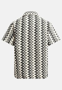 Knocking short-sleeve polo vyrobený z tkané látky, s černo-krémovým cikcak vzorem. Košilový límec, uvolněný střih a texturovaný povrch.