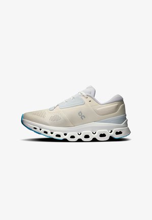 Running shoes in light beige and white, featuring a mesh upper, cushioned sole, and distinctive cut-out pattern on the outsole.